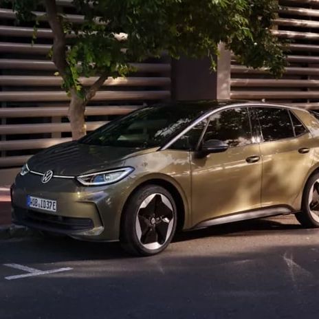 Frau lehnt an einem weißen VW ID.3 