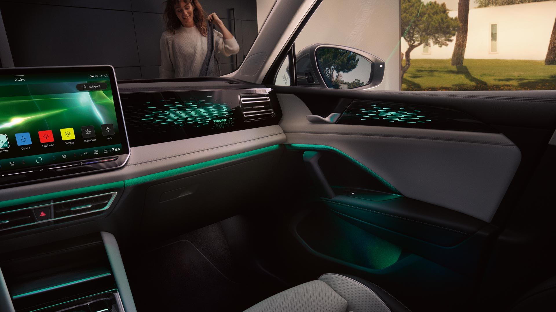 Innenansicht VW Tiguan nachts, Farbdisplay zeigt Einstellungen des optionalen Ambientelichts, Innenraum grün beleuchtet.