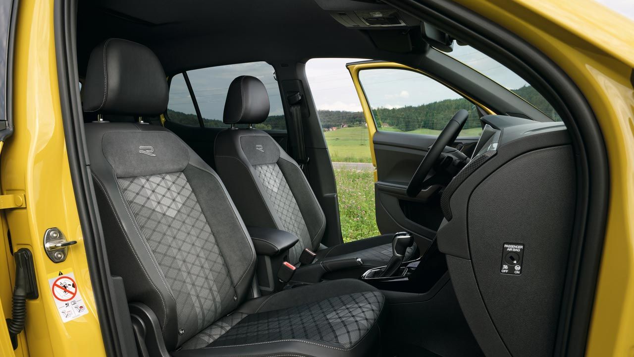 "Blick durch die Beifahrertür des gelben VW T-Cross mit den optionalen Sport Komfortsitzen und der Mittelarmlehne.    "
