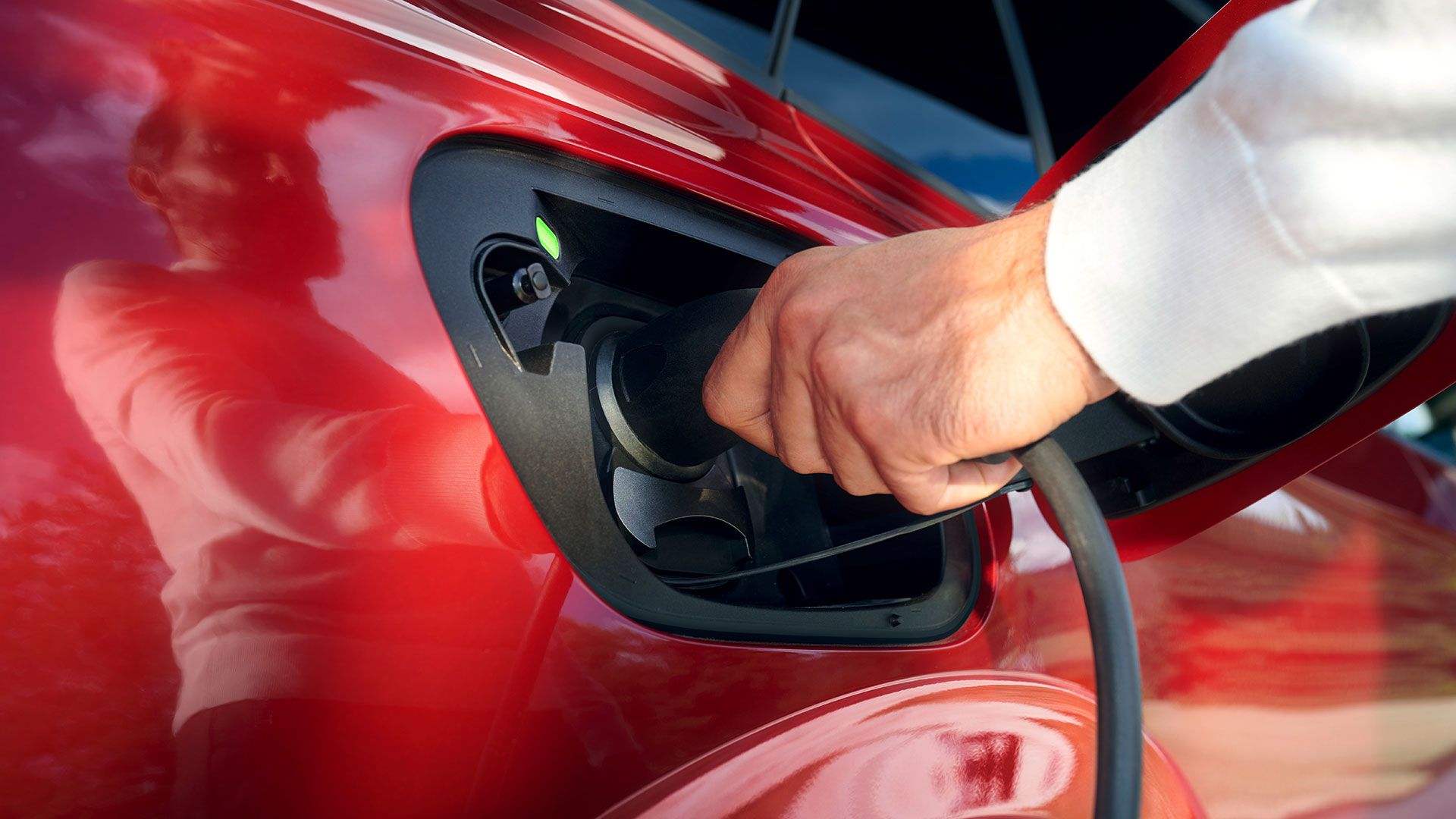 Per Hand wird ein Ladekabel an einen roten VW ID.5 GTX angeschlossen
