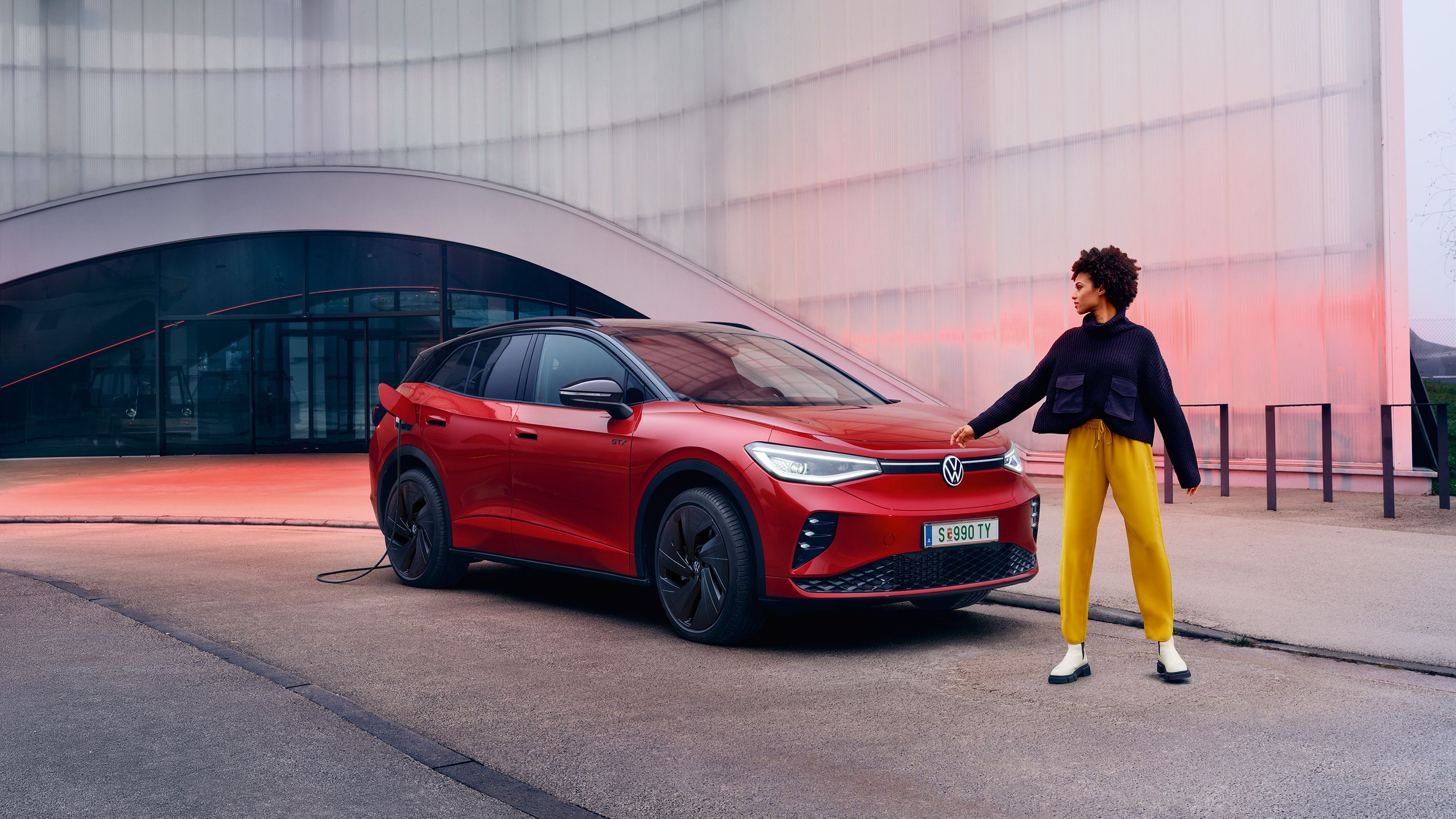Junge Frau steht vor einem roten VW ID.4 GTX