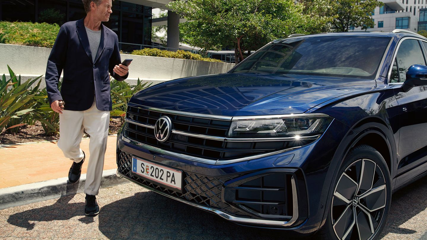 Ein Mann geht an einem parkenden VW Touareg R-Line vorbei.