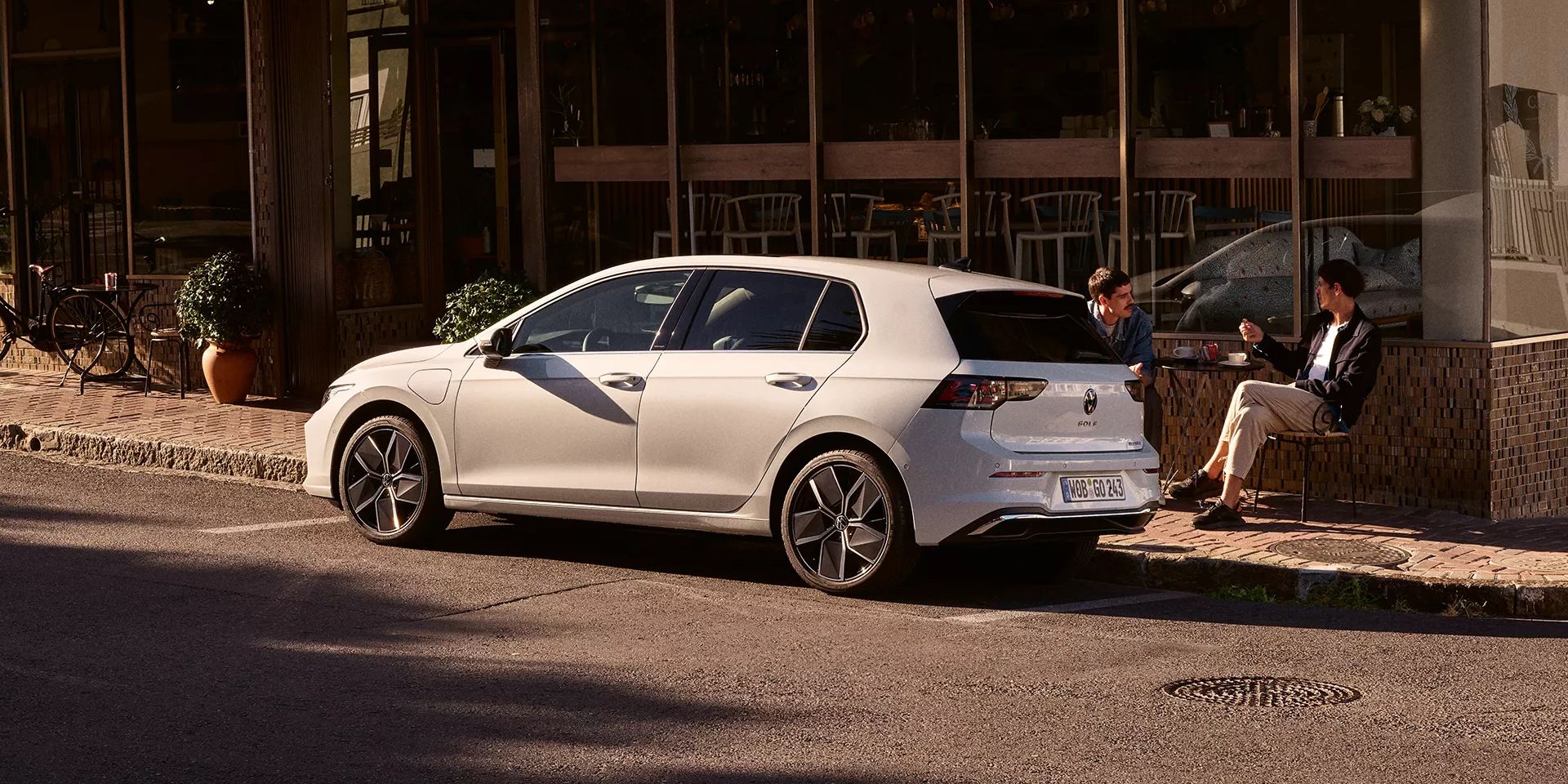 Weißer Golf R-Line parkt seitlich vor einem Restaurant.