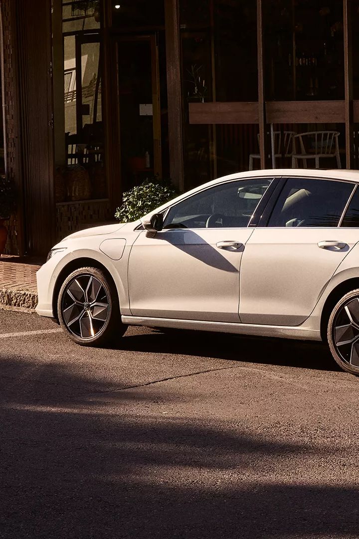 Weißer Golf R-Line parkt seitlich vor einem Restaurant.