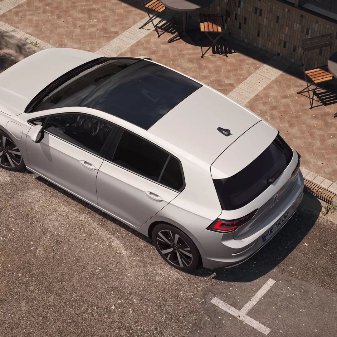 Topview auf einen weißen VW Golf mit Fokus auf das Panoramadach-Aufstell-/Schiebedach. 