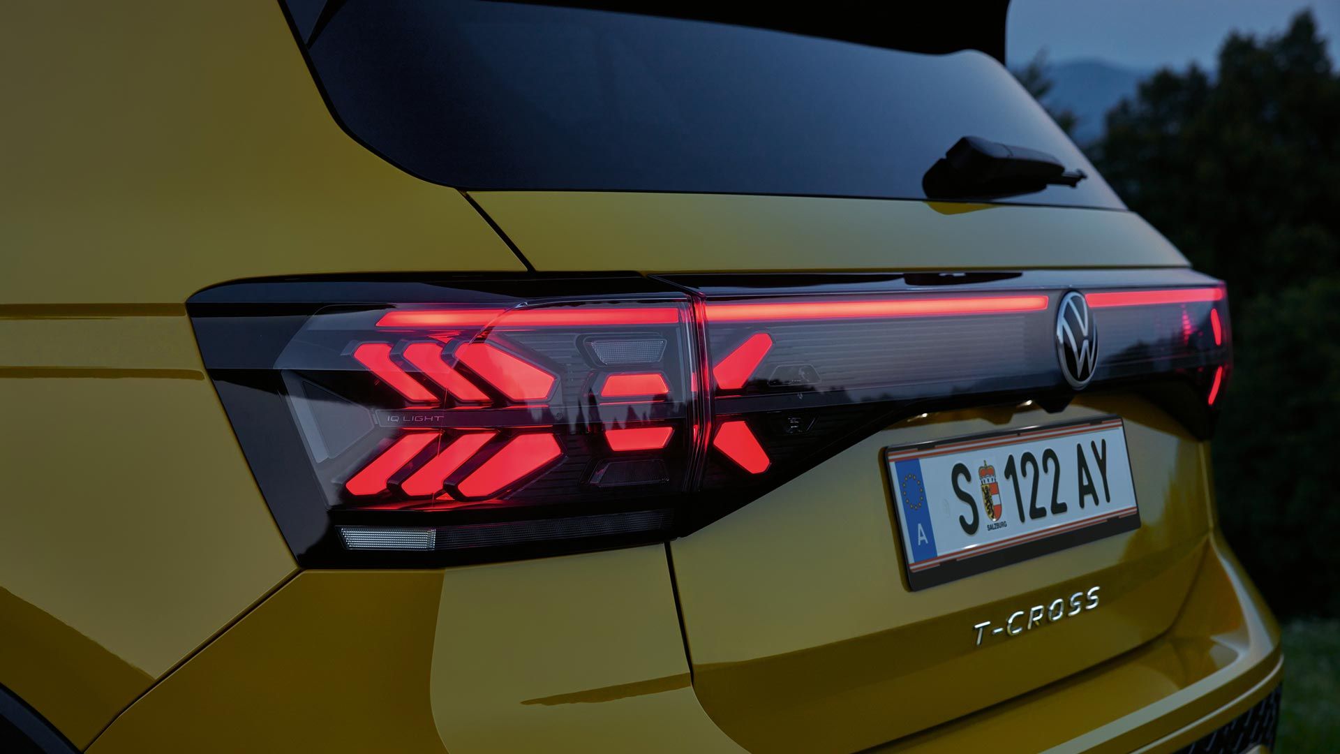 Rückbeleuchtung eines gelben VW T-Cross in Großaufnahme in der Dämmerung.