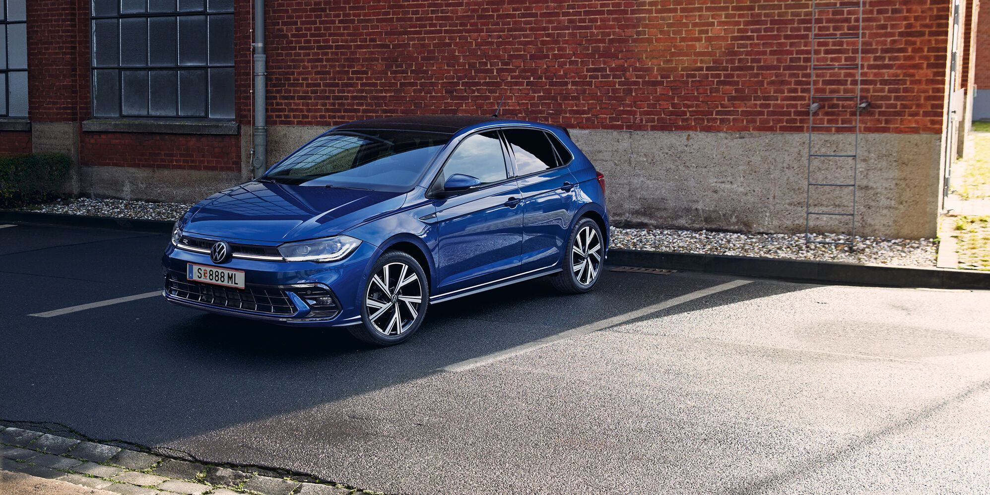 Ein blauer VW Polo steht vor einer Rampe, ein Mann geht am Heck mit den optionalen LED-Rückleuchten vorbei. 