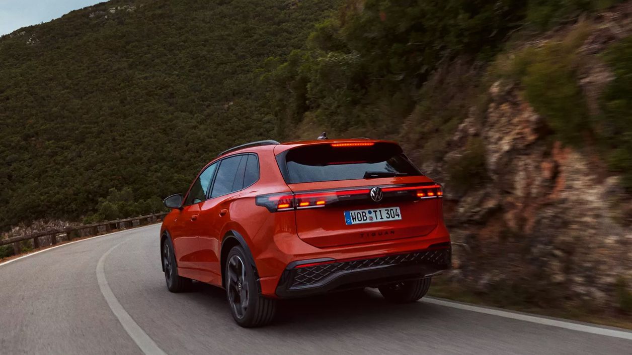 Roter VW Tiguan in Heckansicht fährt durch eine bergige Landschaft.