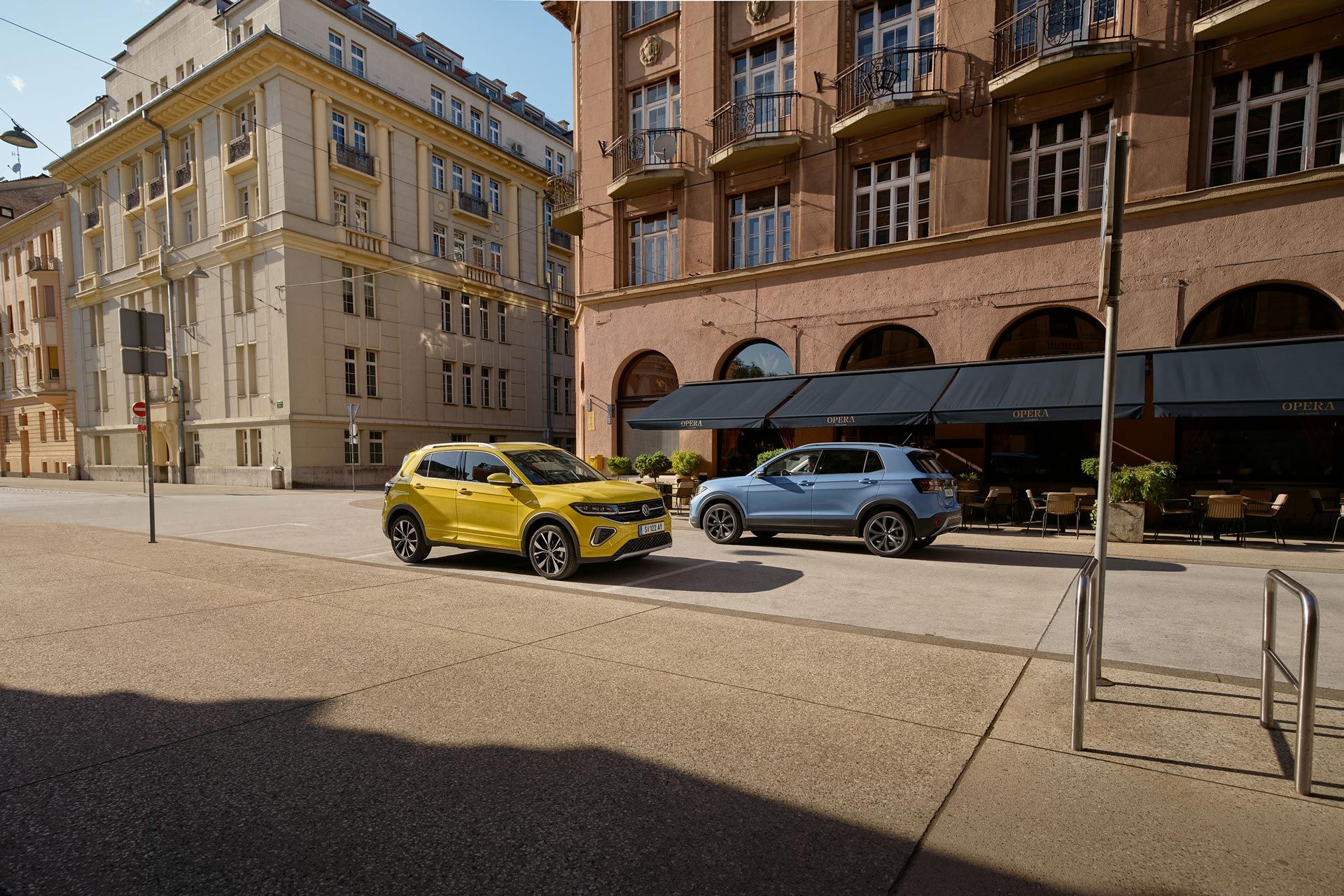 Ein gelber und ein blauer VW T-Cross fahren auf einer Straße aneinander vorbei.