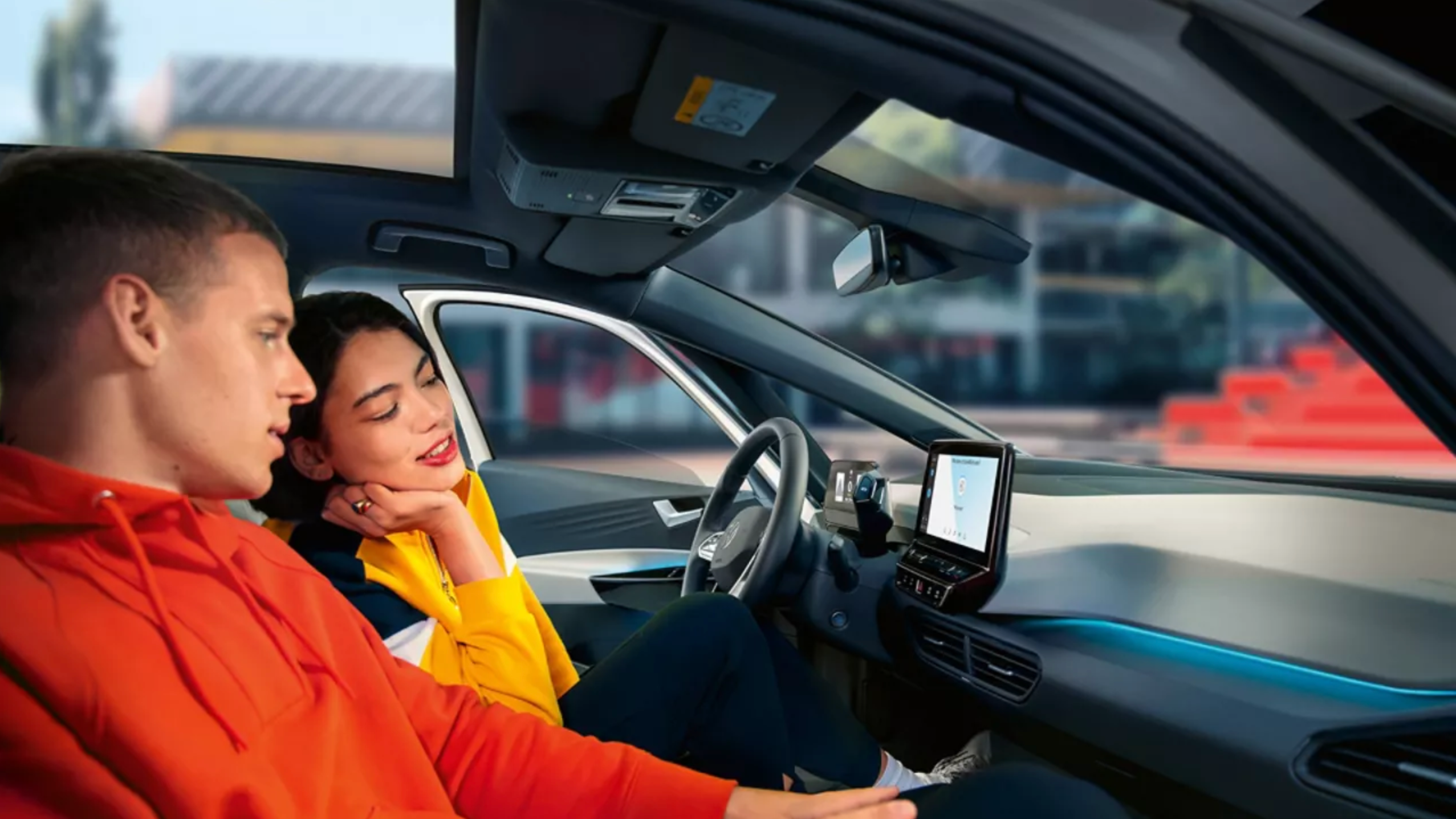 Personen auf den Vordersitzen im VW ID.3 schauen sich das Radiodisplay an