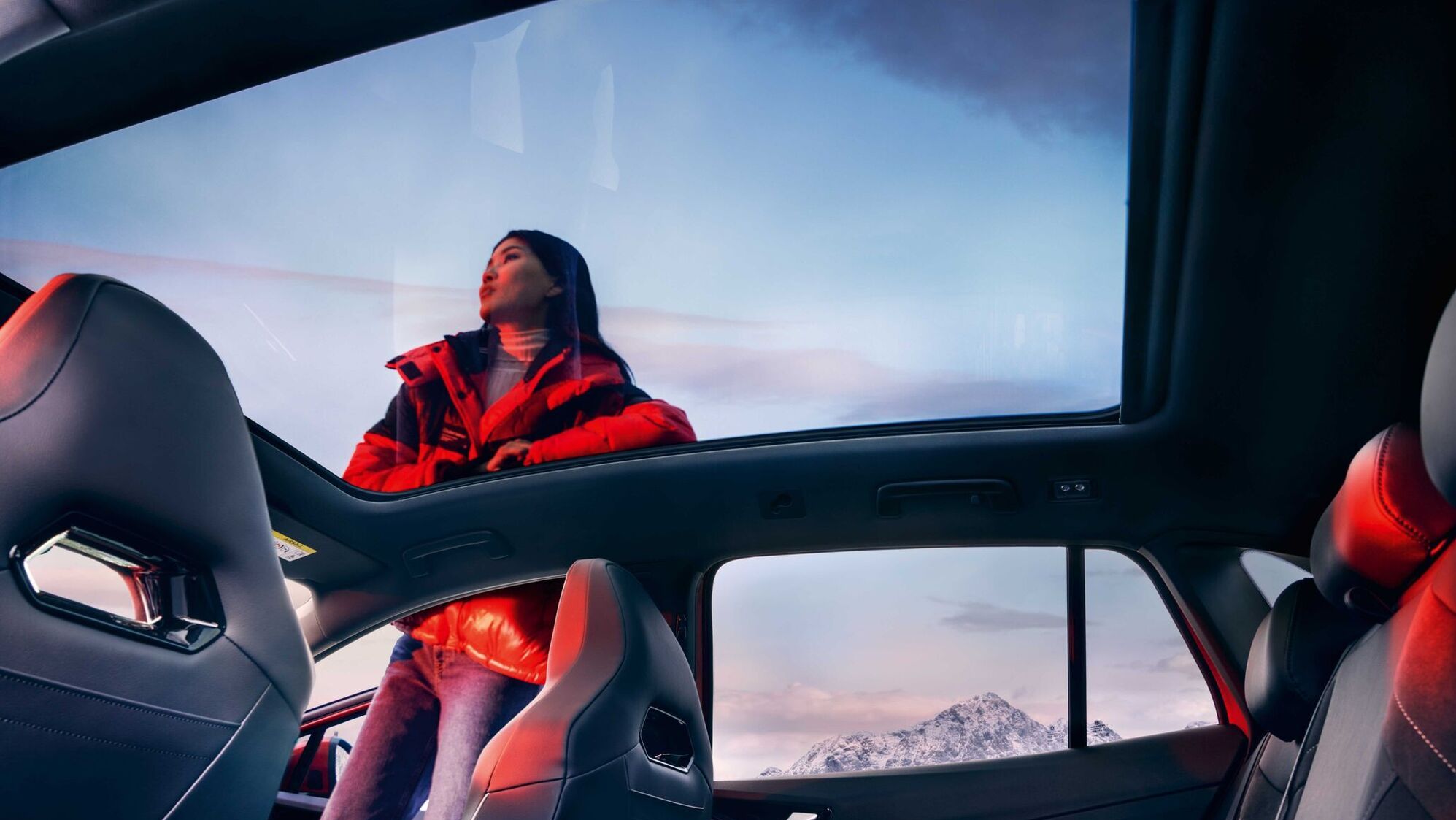 VW ID.4 GTX Blick von innen durch Panoramadach auf Frau neben dem Fahrzeug.