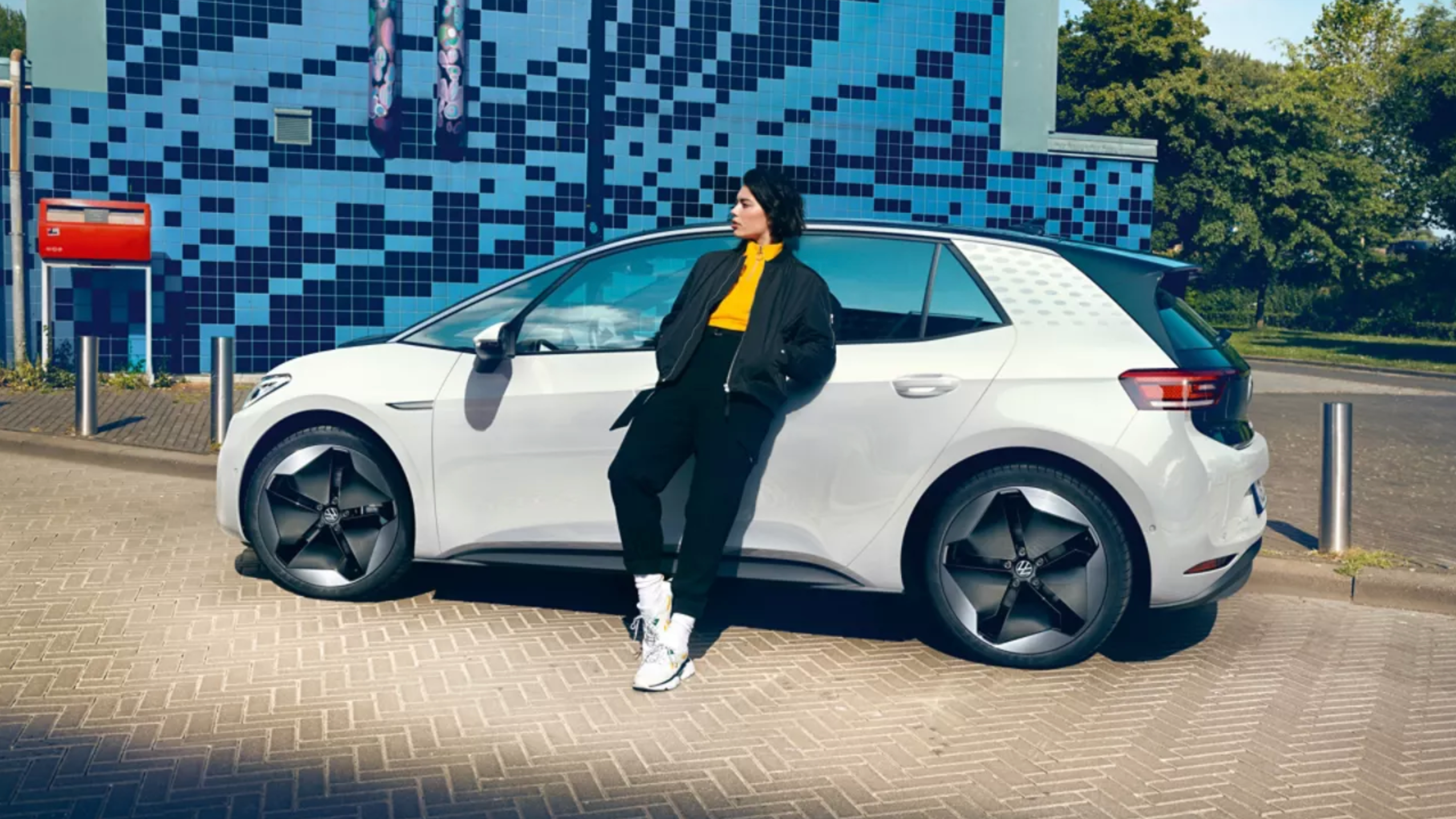 Frau lehnt am Straßenrand geparkten VW ID.3