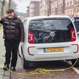 Ein weißer Caddy Kastenwagen fährt dynamisch durch eine belebte Stadt.