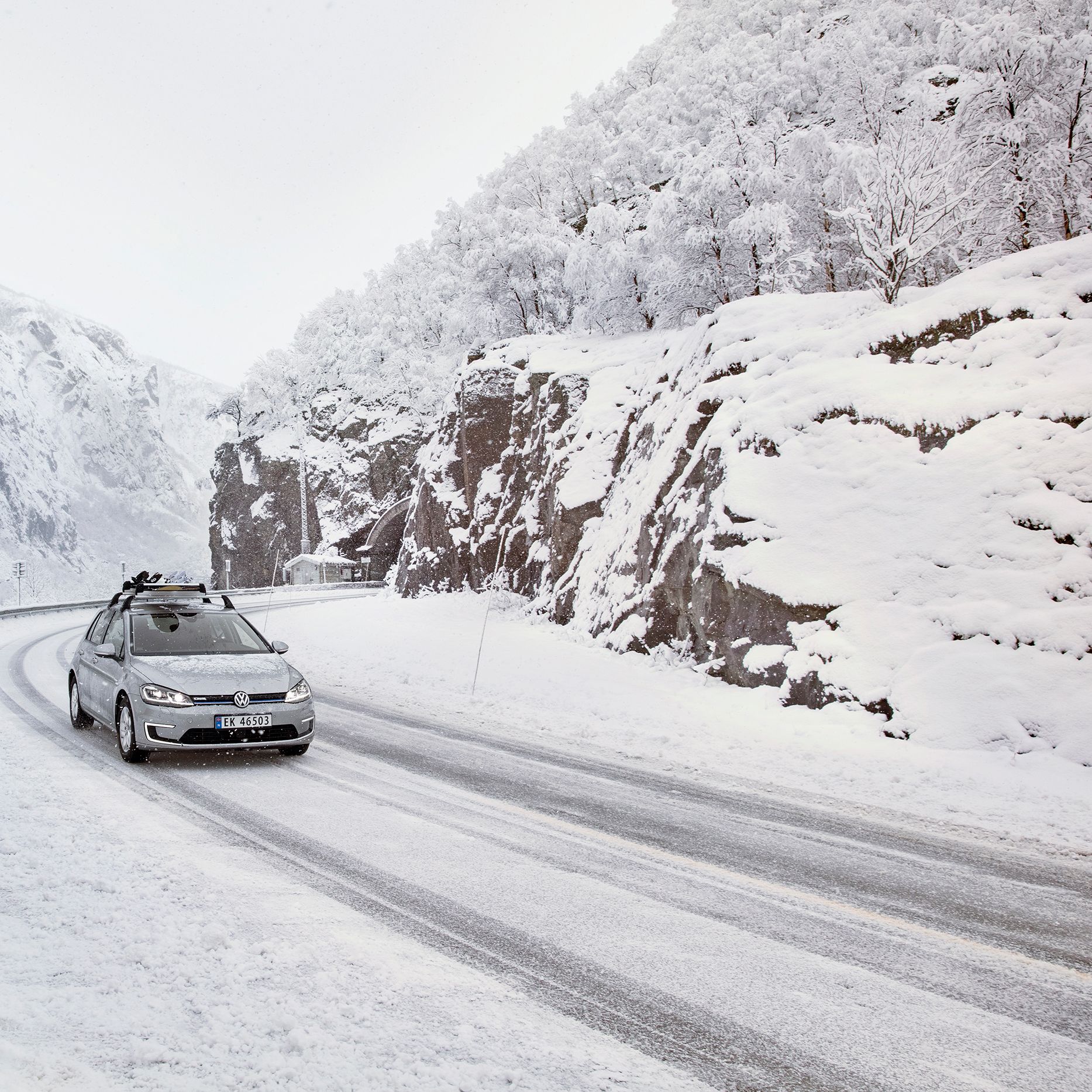 e-Golf mit Snowboardhalter fährt durch eine verschneite Berglandschaft
