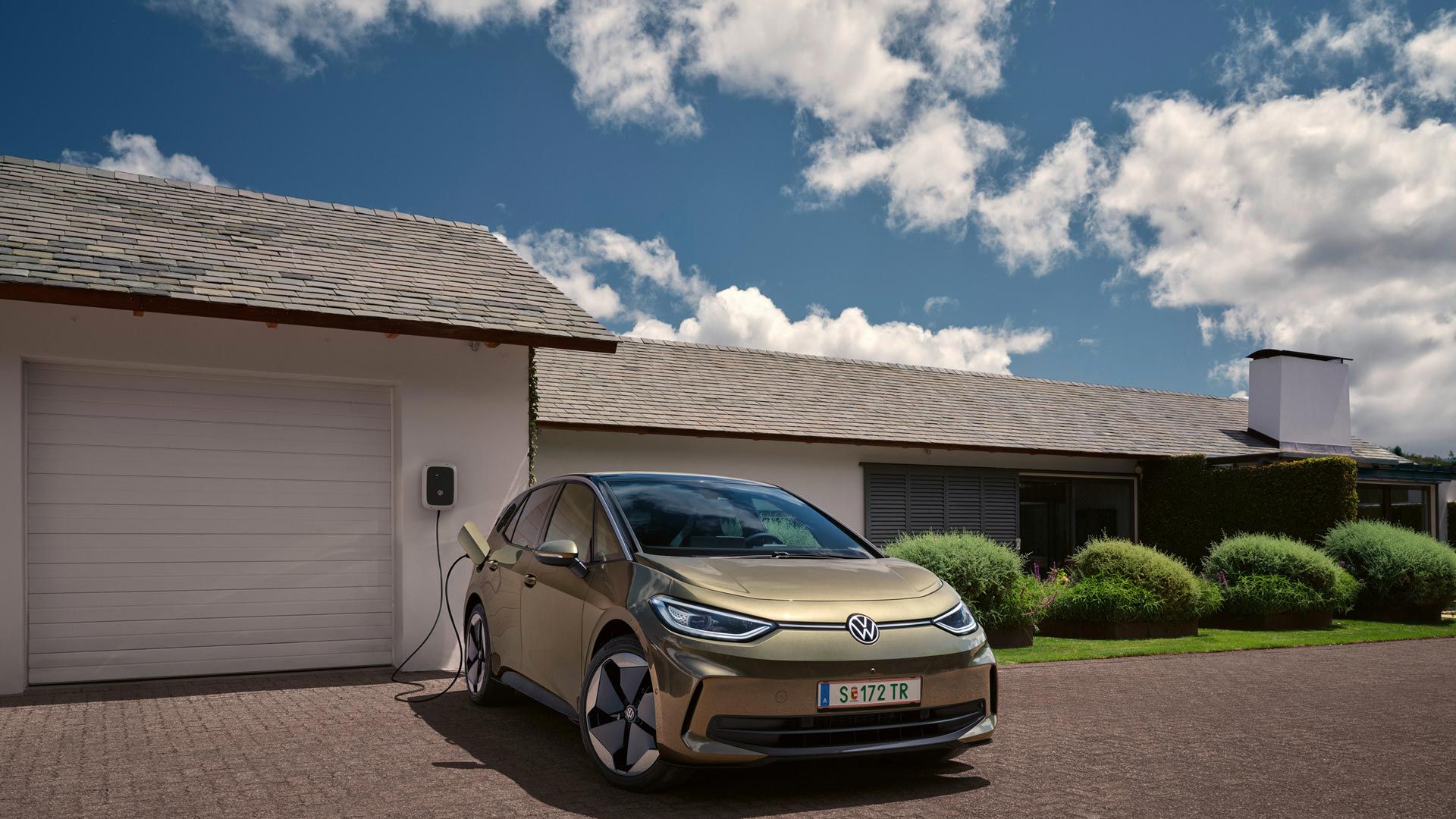 Der VW ID.3 wird an einer Wallbox geladen im Hintergrund ein Einfamilienhaus