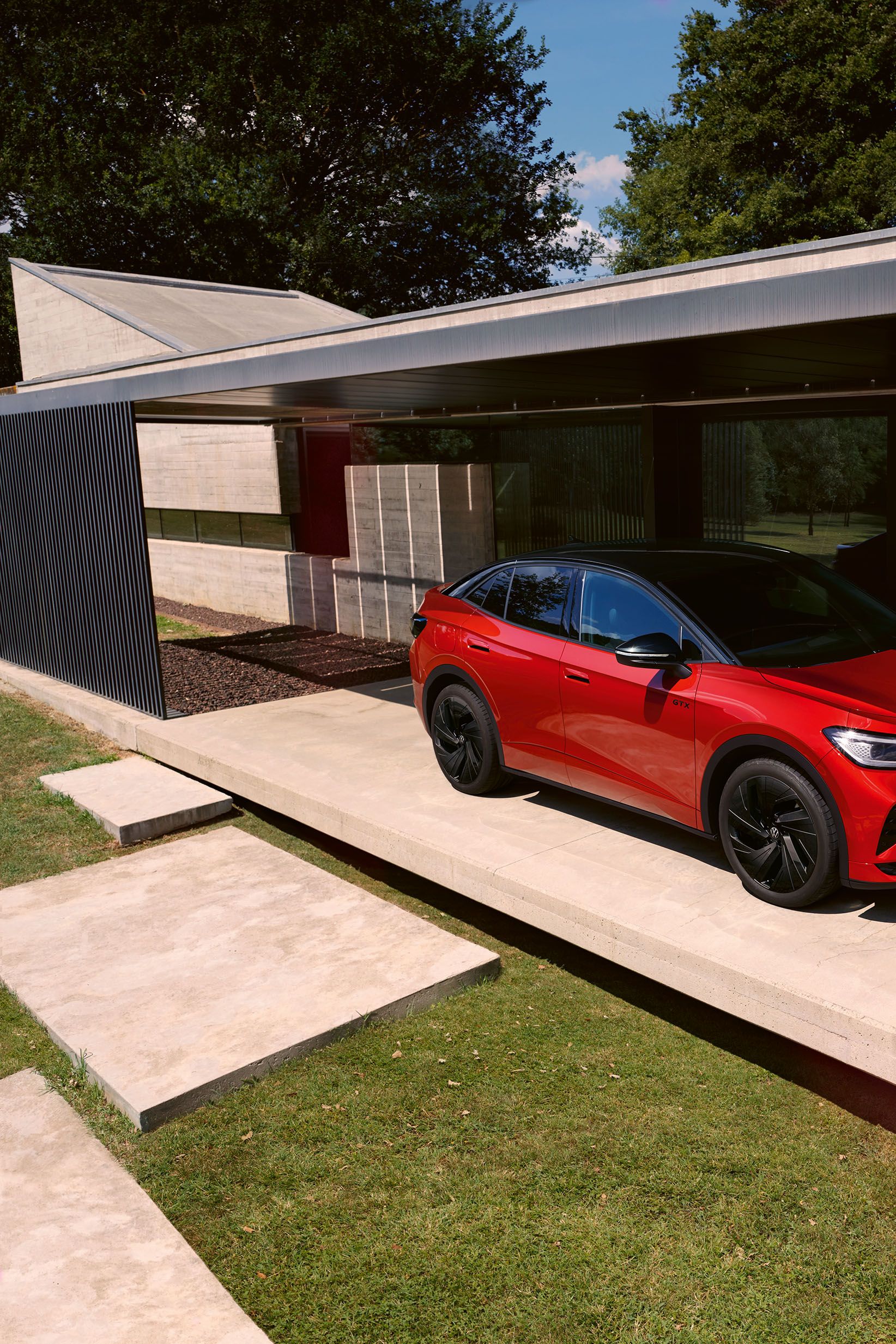 Roter VW ID.5 GTX von schräg vorne in einem modernen Carport, ein Mann geht vor der Motorhaube entlang