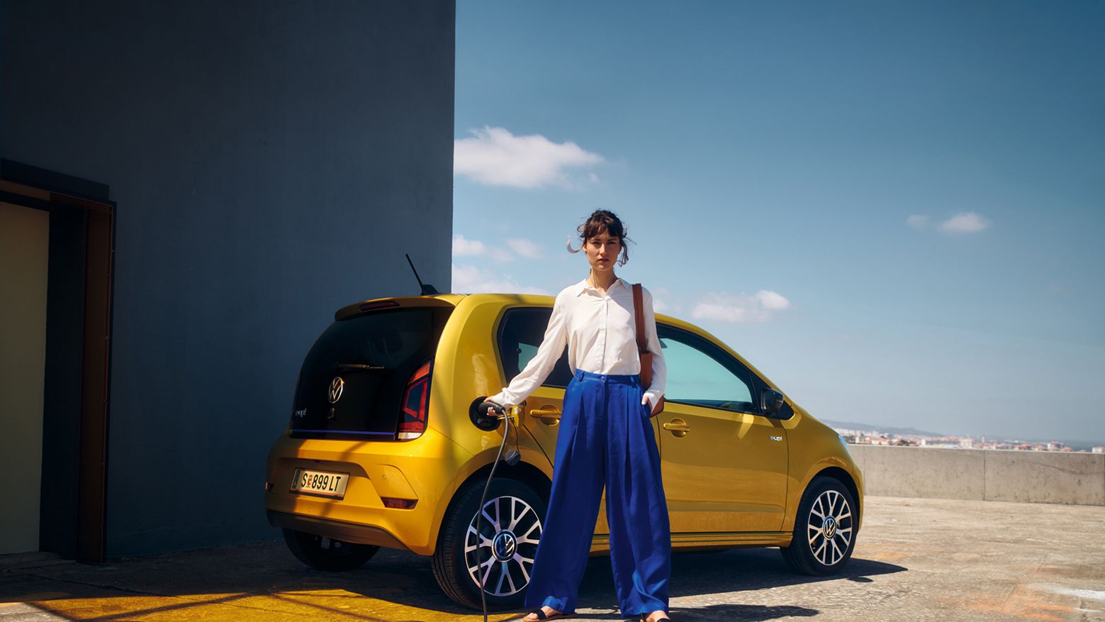 Eine Frau steht vor einem VW e-up! 