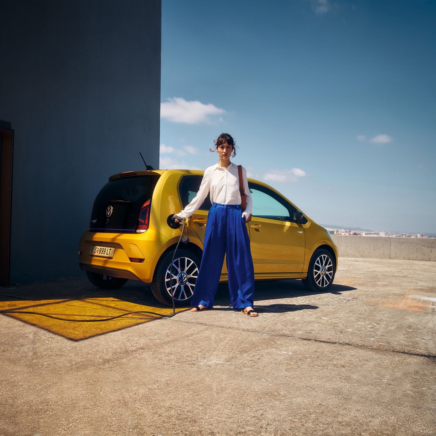 Eine Frau steht vor einem VW e-up! 
